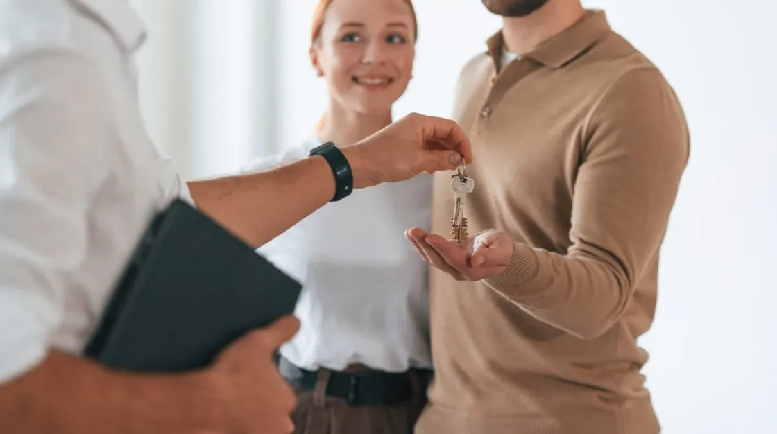 Finance broker handing keys to a smiling couple after loan approval